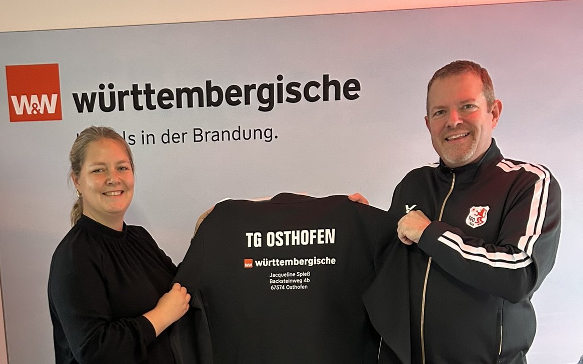 Jacqueline Spieß (Generalagentur Württembergische) und Martin Preuß (TGO Badminton) halten den neuen Trainingsanzug mit Werbeaufdruck